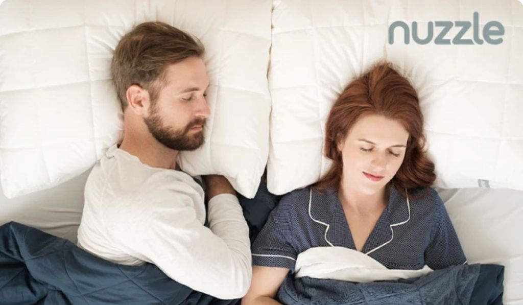 A man and woman sleeping on Nuzzle pillows in bed
