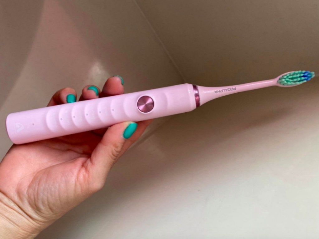 lady holding a pink electric toothbrush