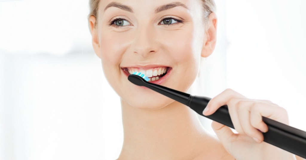 girl smiling brushing her teeth with en electric toothbrush