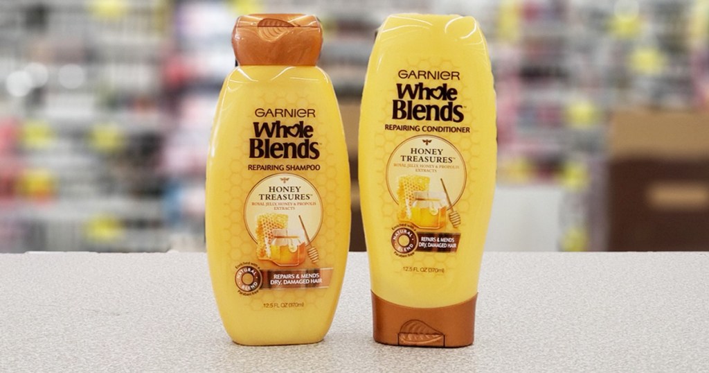 two yellow and brown bottles of Garnier Whole Blends shampoo and conditioner on checkout counter at Walgreens