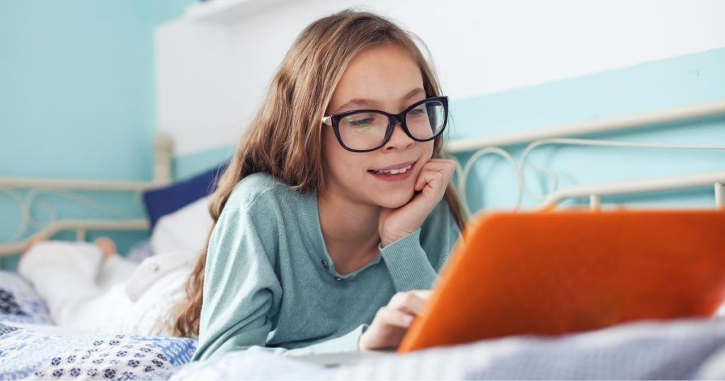 A girl wearing glasses and looking at laptop screen