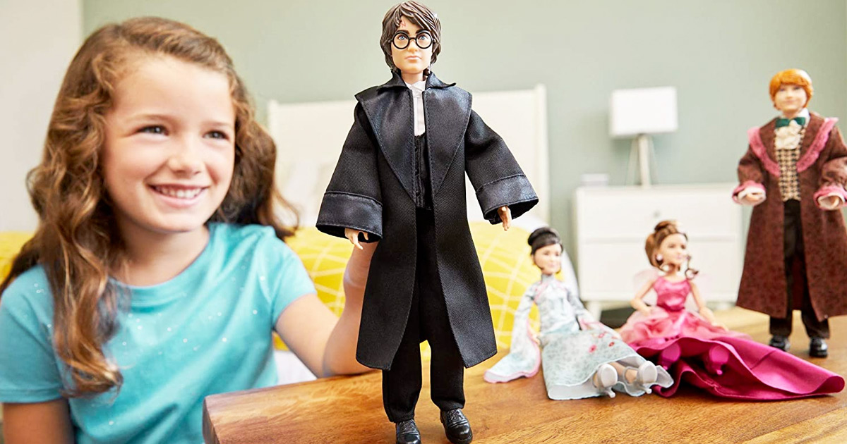 girl in blue shirt playing with Harry Potter doll on wood table with other Harry Potter character dolls in background