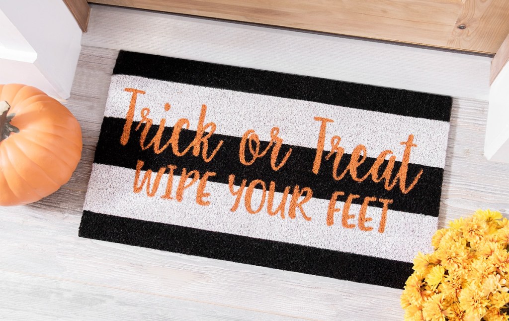 black and white striped doormat that says trick or treat wipe your feet in orange