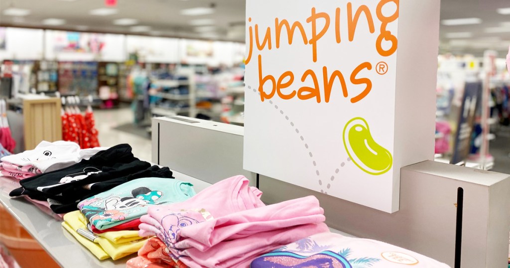jumping beans sign above store display of folded girls graphic tees