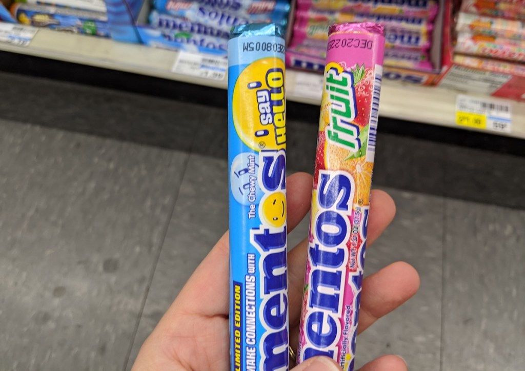 hand holding two packs of Mentos mints