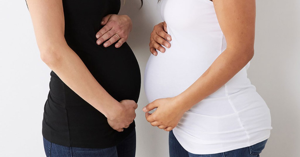 two pregnant woman holdng their bellies facing each other