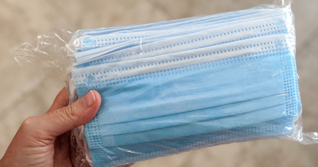 person holding a package of blue disposable face masks
