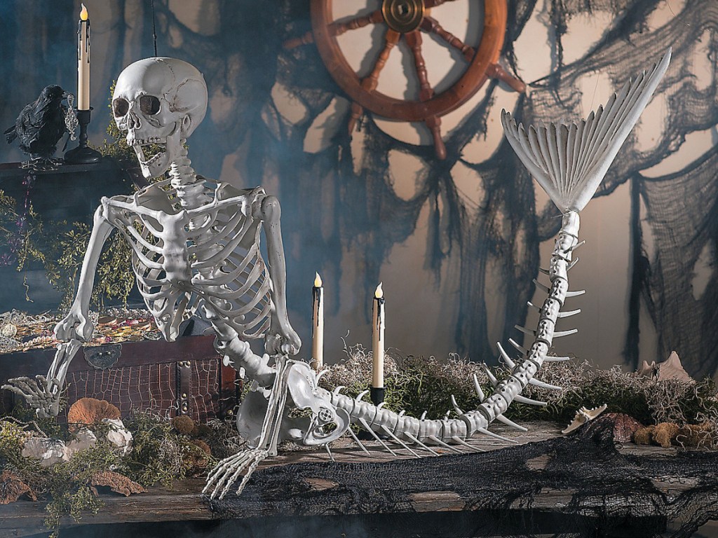 large lifelike mermaid skeleton halloween decor sitting on top of the spooky table