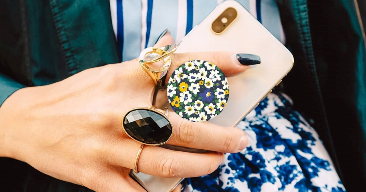 woman holding a pink cell phone with a floral pop socket