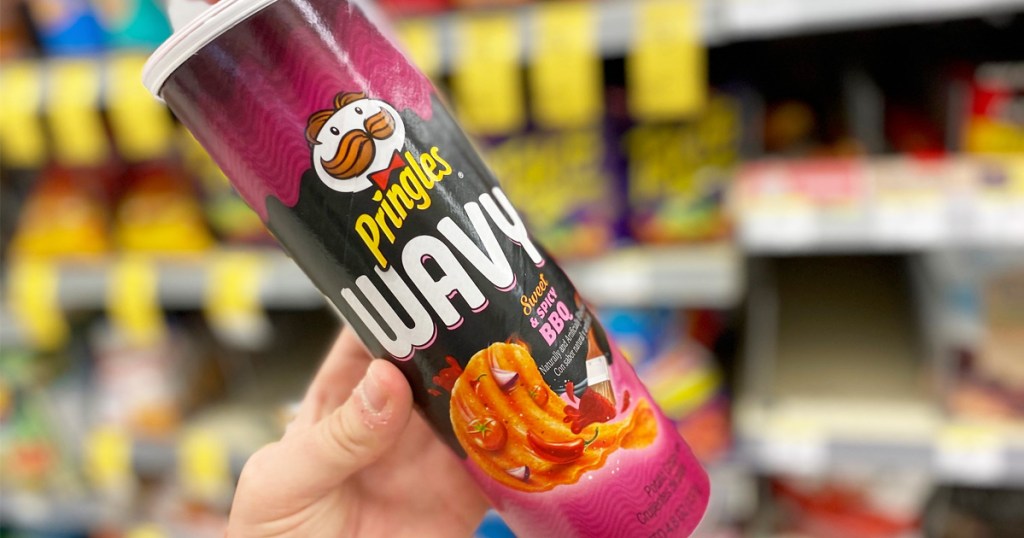 person holding up a purple and black can of Pringles Wavy chips in sweet & spicy bbq flavor