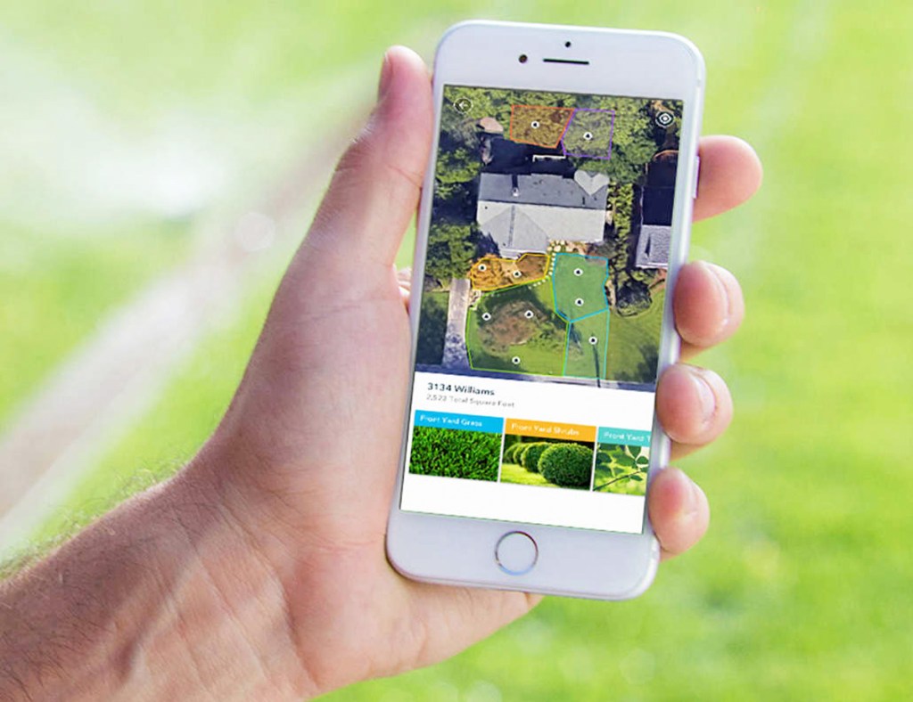person holding white iphone with rachio app showing different watering zones