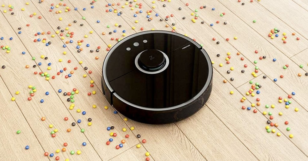 round black robotic vacuum cleaning up spilled candy on hardwood floor