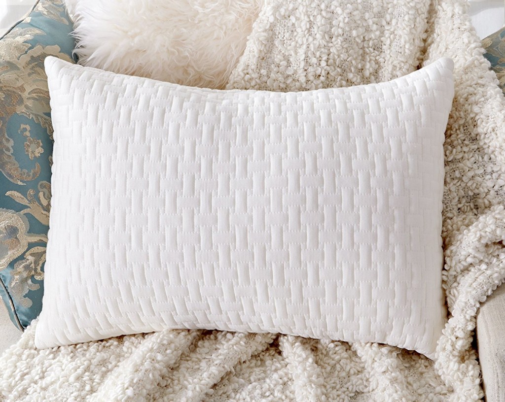 white memory foam bed pillow on a white fuzzy blanket on a chair