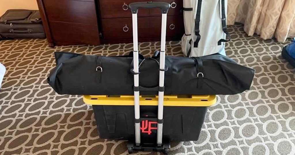 luggage rack with plastic storage bin and black luggage bag stacked on it