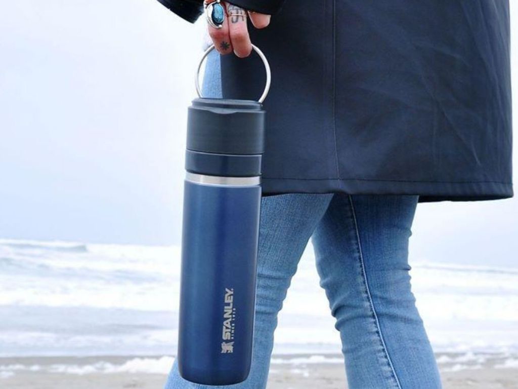 stanley go 24 oz water bottle carried by woman walking on beach