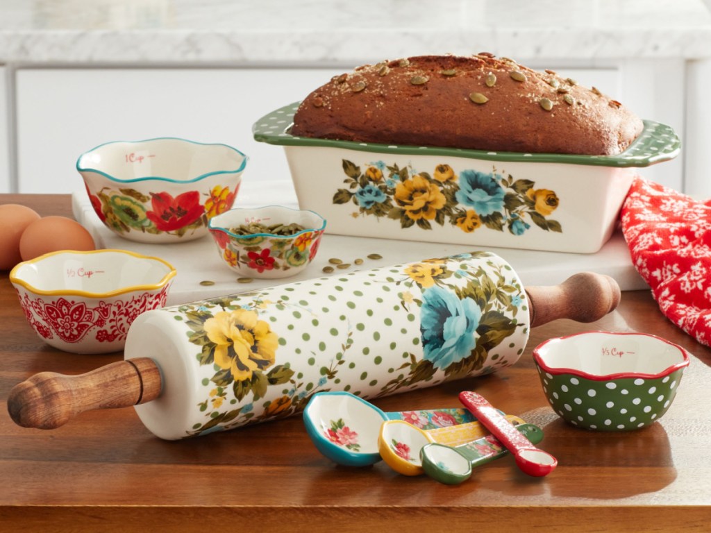 bread in white floral design loaf pan, bowls, measuring spoons, and rolling pin on kitchen counter