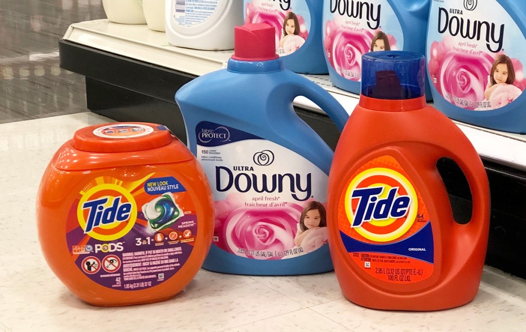 orange container of tide pods and tide liquid with a blue bottle of downy fabric softener grouped together