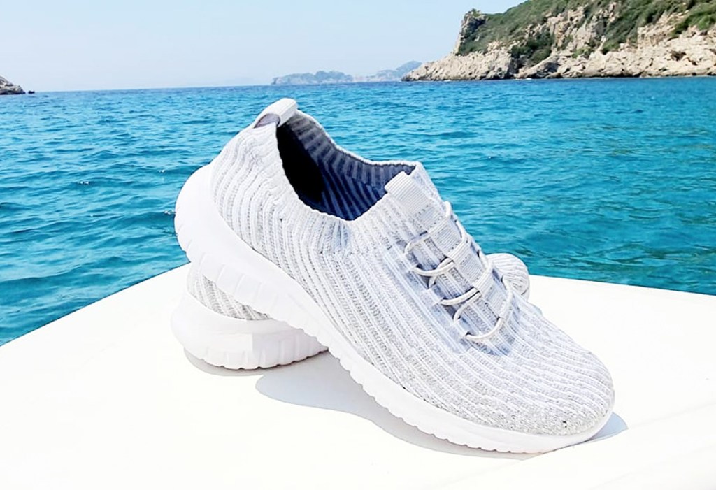 pair of light grey knit walking shoes on edge of white boat in water