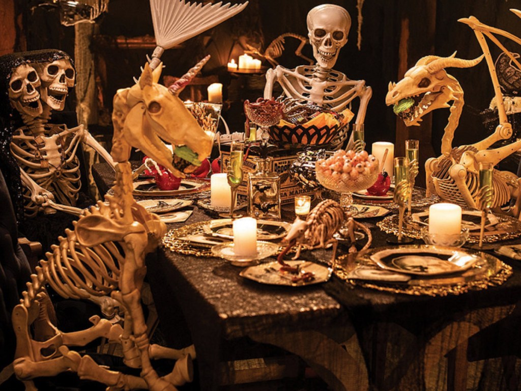 unicorn skeleton sitting at a table with other skeletons 