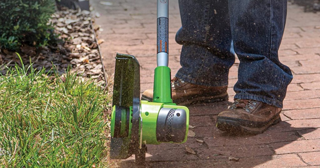 greenworks cordless hedge trimmer shown with mans feet