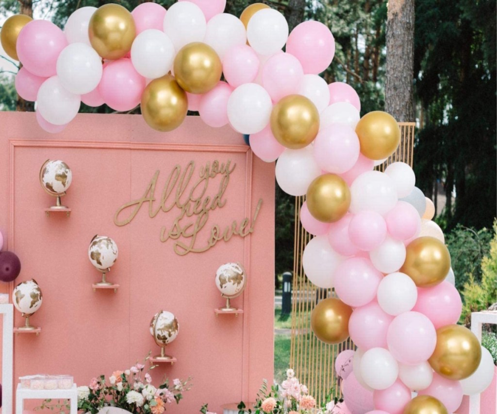 white, pink, and gold balloon arch at outdoor party