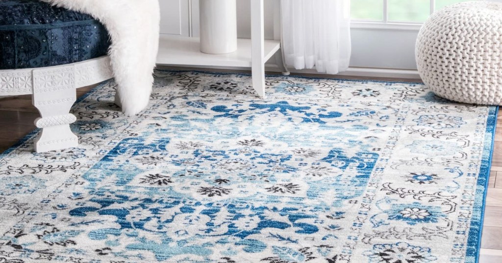 cream and blue oriental rug on hardwood floor near white and blue ottoman with throw blanket