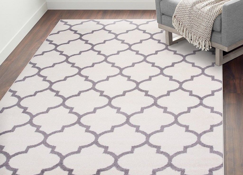 white and grey trellis print area rug on hardwood floor near grey accent chair