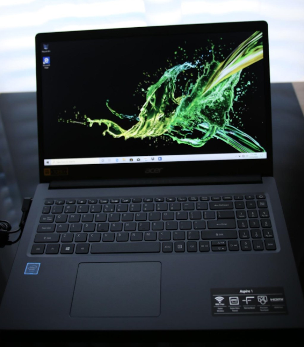 open acer laptop on black desk in front of window