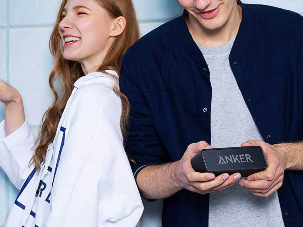 couple laughing holding a bluetooth speaker