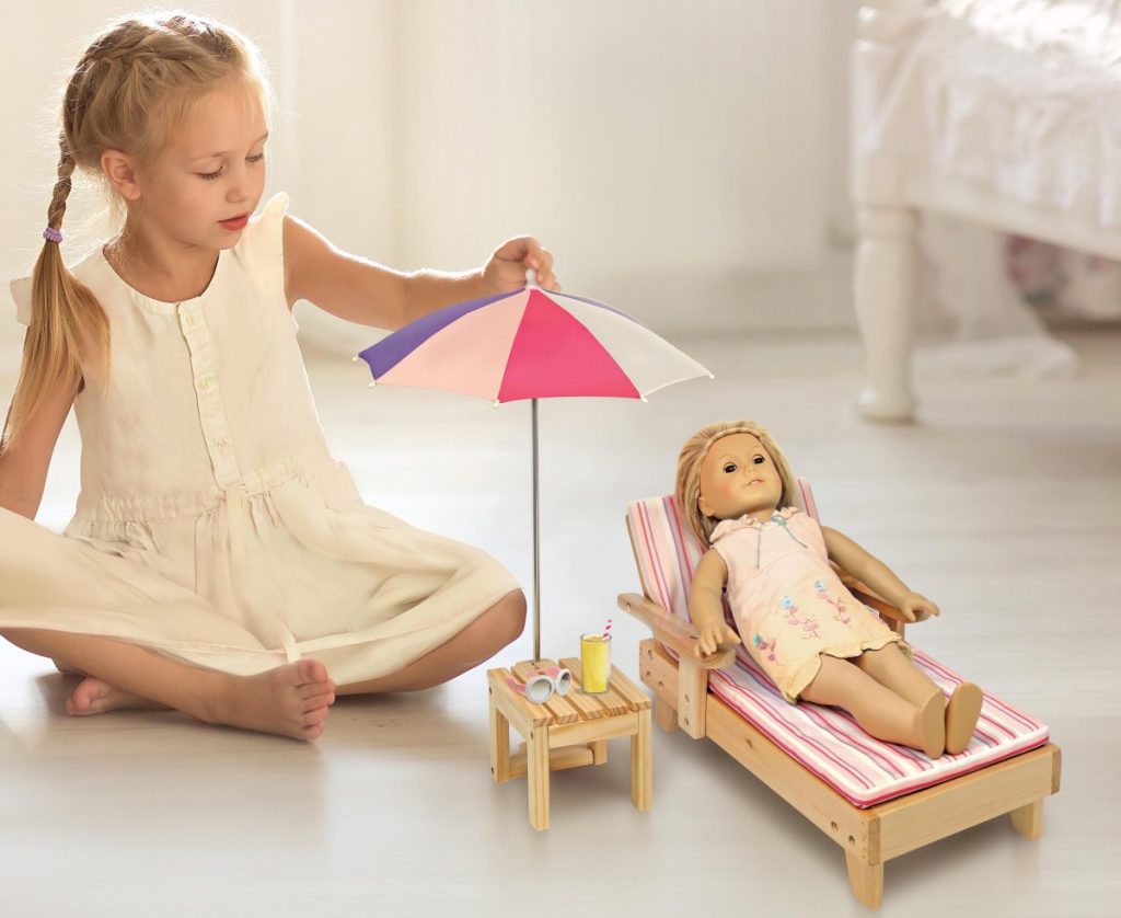 girl playing with her doll who is laying in beach lounger