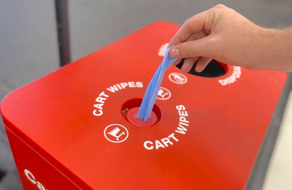 hand putting a blue cart wipe from red box