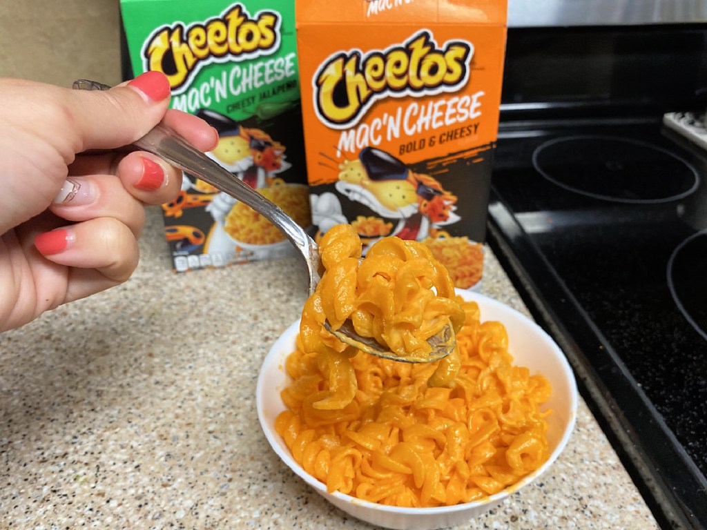 cheetos mac 'n cheese in bowl on coutertop with woman holding spoonful