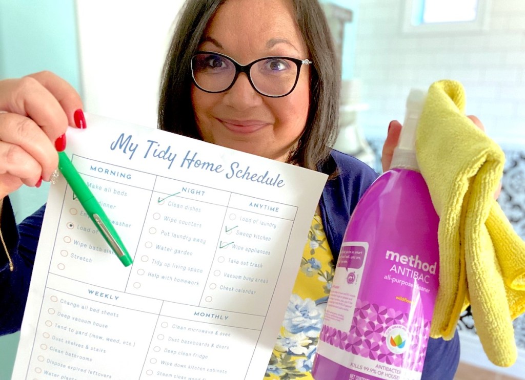 woman holding printable chore chart with cleaning products