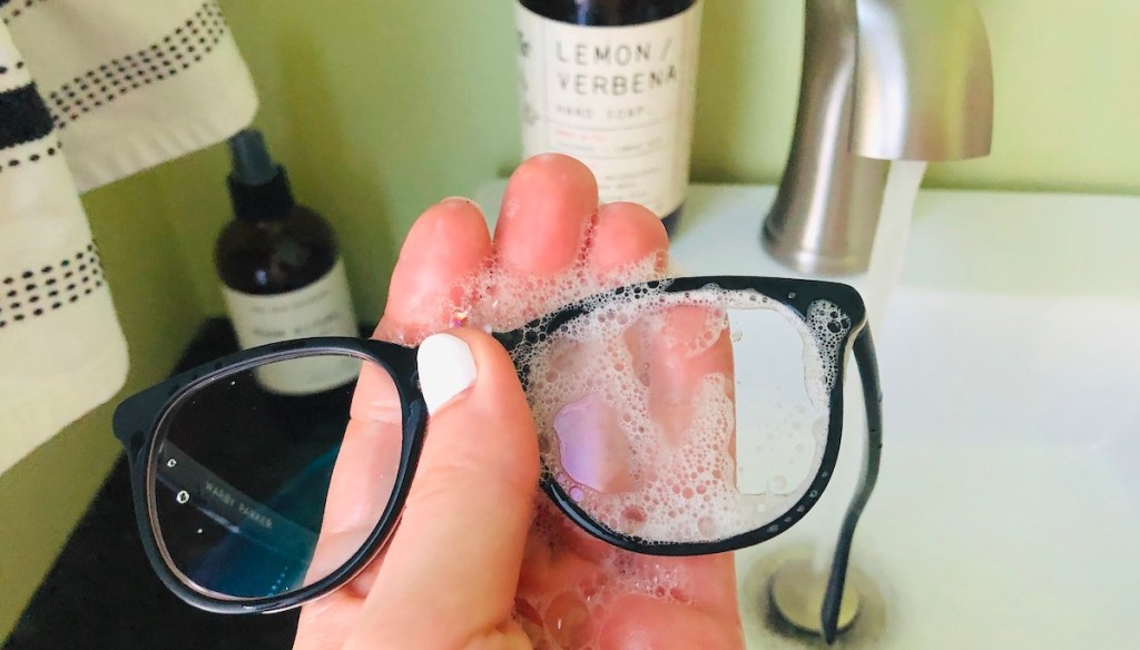 hand holding eyeglasses with soap suds