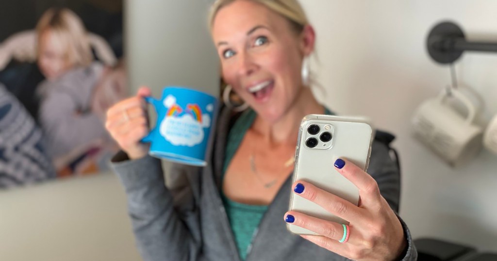 woman holding iphone and coffee mug