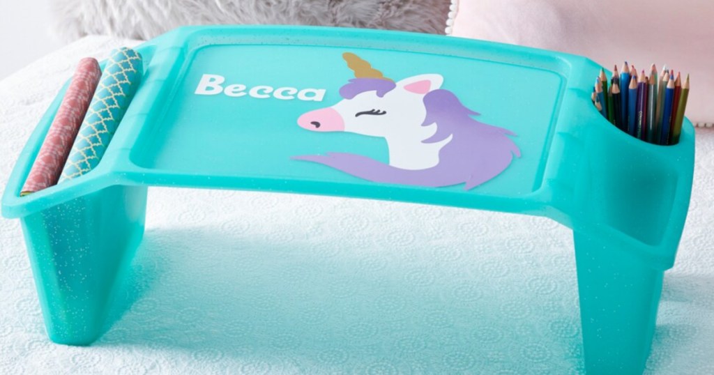 light teal kids lap tray with a unicorn decal on top and side pockets