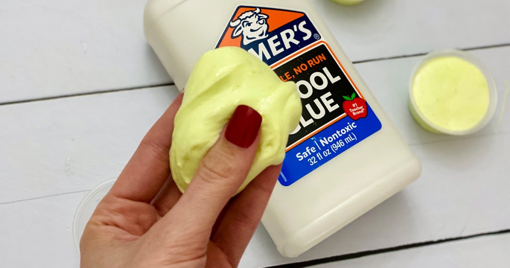 hand holding yellow puffy diy slime in front of elmer's glue