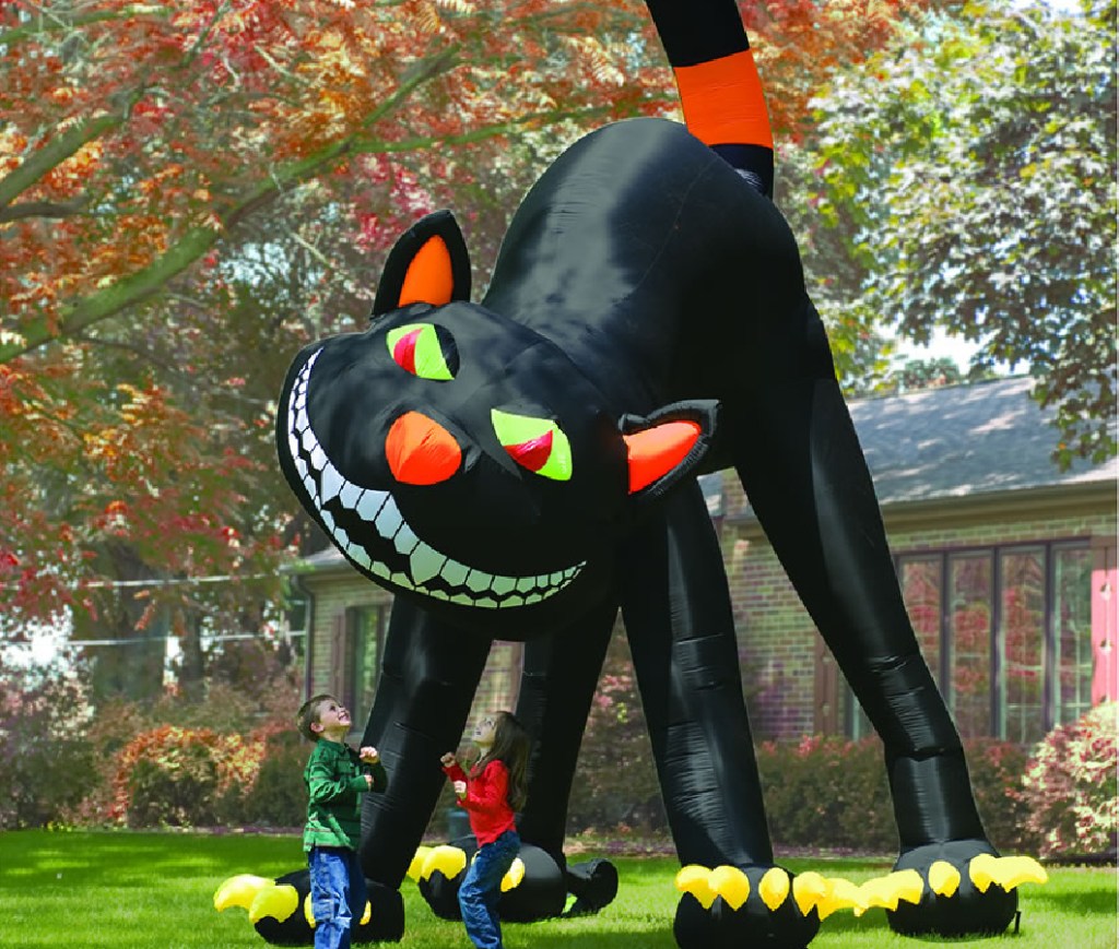 kids playing by giant inflatable cat decoration in front yard