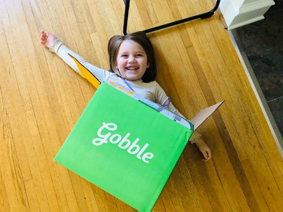 little girl laying under a gobble box