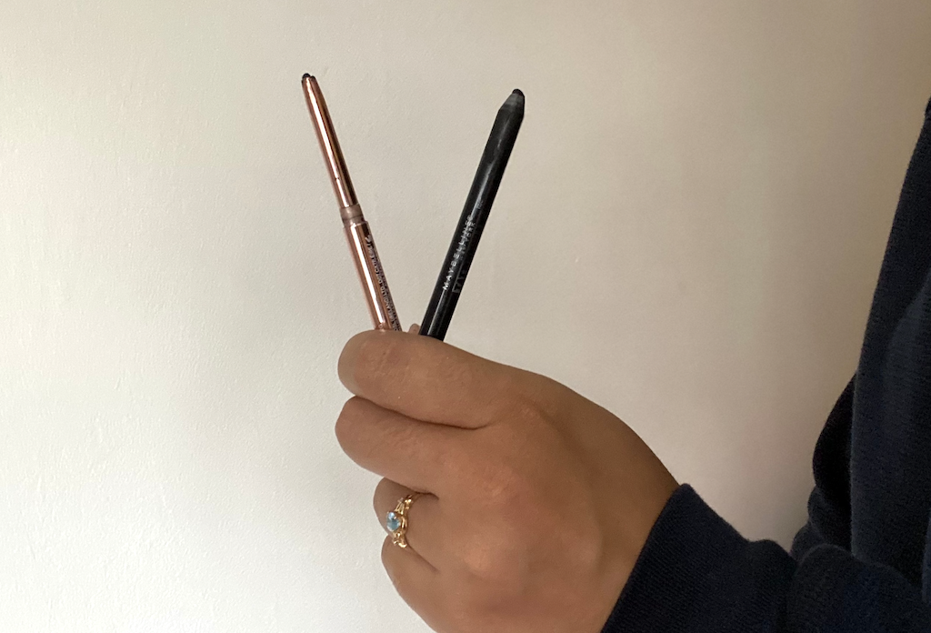 holding two eyeliner pencils 