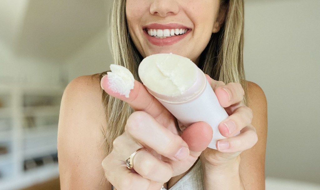 woman holding up stick of deodorant with it on her finger