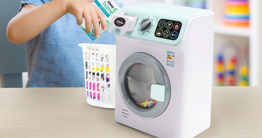 girl playing with toy washing machine and small basket of laundry