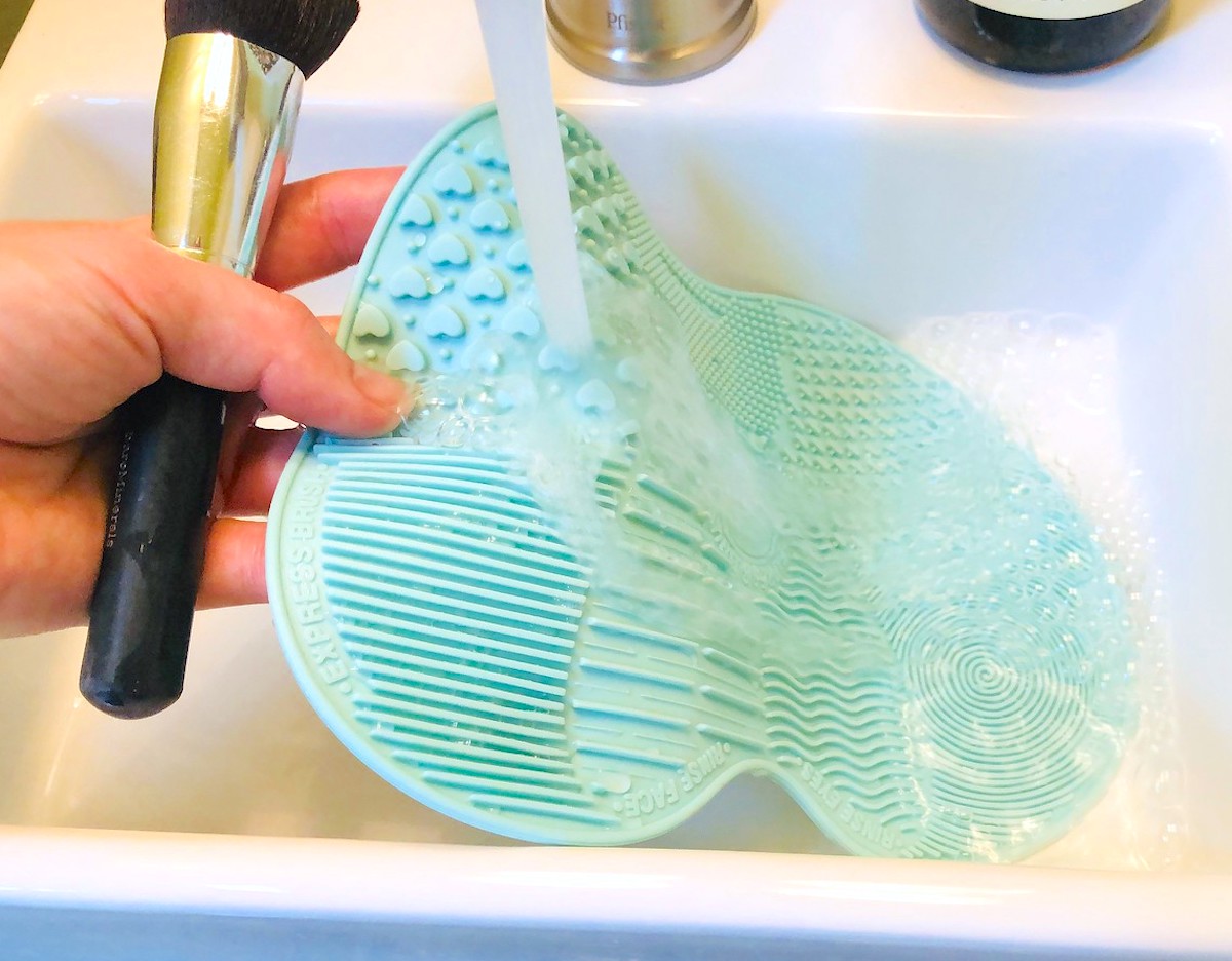 blue silicone makeup brush mat under running faucet