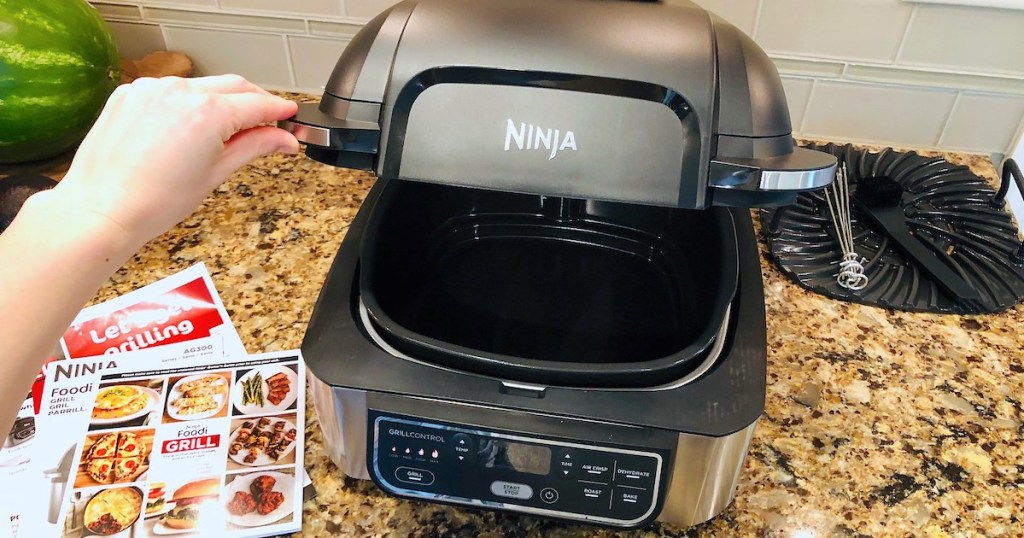 hand holding lid to ninja foodi grill on granite countertop