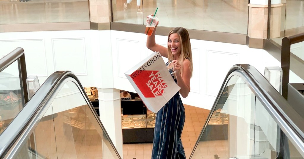 woman holding nordstrom sale shopping bag going down escalator