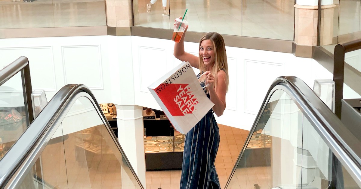 woman holding nordstrom sale shopping bag going down escalator 