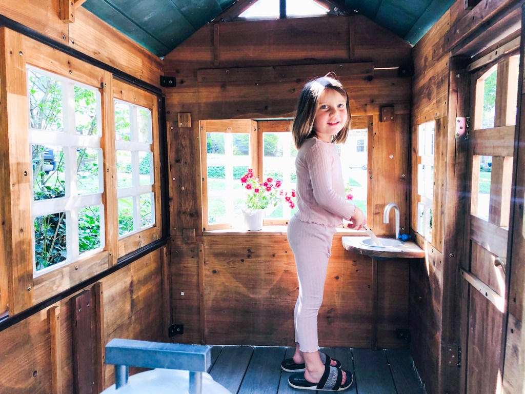 girl standing inside of kids playhouse