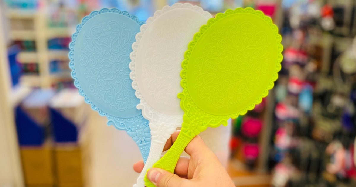 hand holding 3 mirrors, each in a different color, in a store