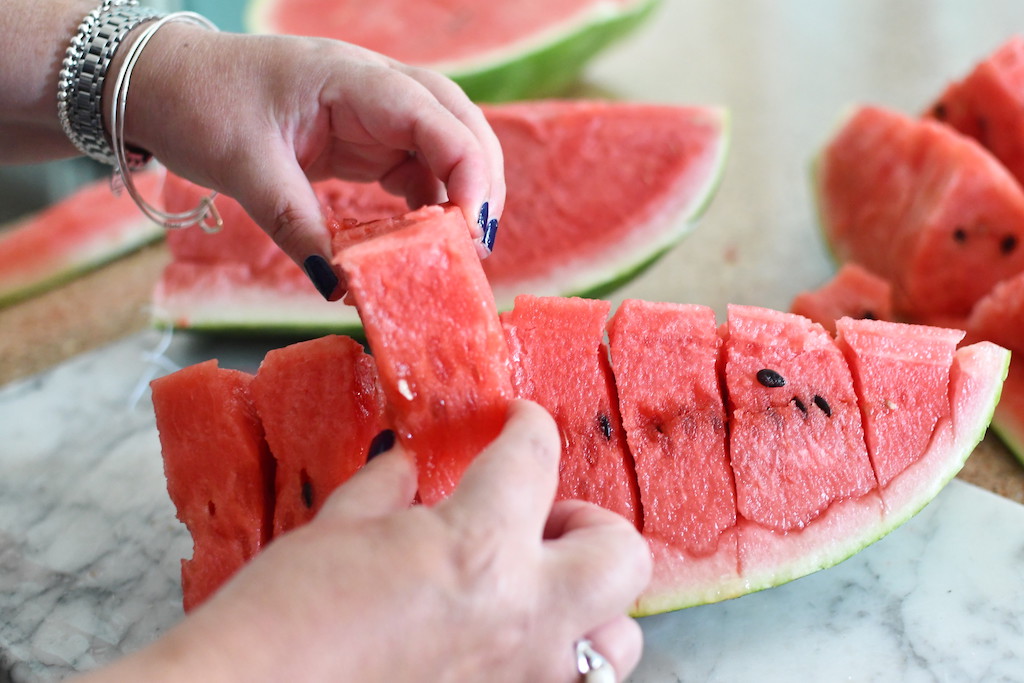 woman pulling out wedge of watermelon 
