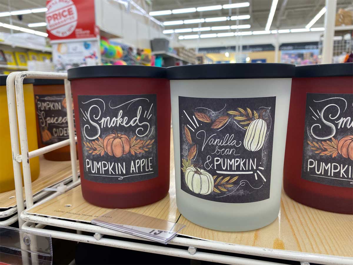glass jar candles with fall scents on a store display shelf